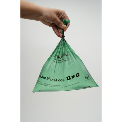 Hand holding a Define planet Grab n Go green plastic bag with branding on a white background at Harmony Pet Supplies Scarborough
 