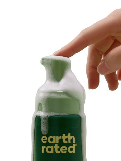 Hand holding a green bottle of Earth Rated product with foam.
