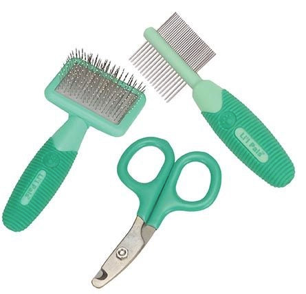 Set of green pet grooming tools including a brush, comb, and scissors on a white background.