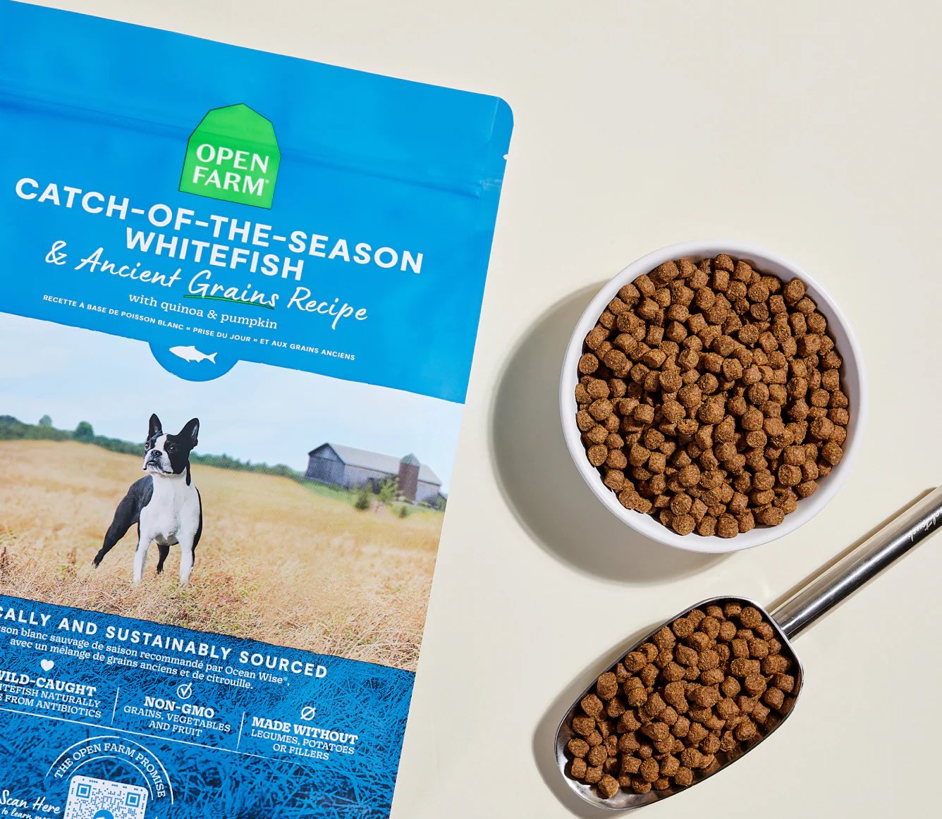 Open Farm dog food package with a bowl of dog food and a scoop on a light background